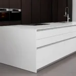 White Kitchen Island with an Integrated Stovetop and Sink in a Modern Dark wood Kitchen Setting