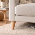 Untitled-1 | Securadeal Beige Sofa with a Wooden Leg on a Textured Cream Rug a Side Table with a Mug and Books in the Background