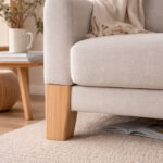 Beige Sofa with Wooden Legs in a Cozy Living Room a Magazine Under the Seat and a Side Table with a Mug in the Background