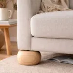 Beige Upholstered Sofa with a Rounded Wooden Foot on a Light Rug in a Cozy Living Room