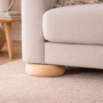 Untitled-1 | Securadeal Close up of a Beige Upholstered Sofa with a Round Wooden Leg Resting on a Light Carpet