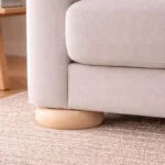 Untitled-1 | Securadeal Low Wooden Sofa Leg Resting on a Round Post Under a Light Beige Couch on a Textured Rug