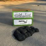 0be20b5f-0356-4d58-8eb7-505f97c17b1d | Securadeal Box Labeled Patchpal Pothole Solution on a Street with a Row of Black Circular Pothole Patches in Front