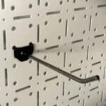 Curved Metal Pegboard Hook Protruding from a Perforated Wall Panel with a Black Mounting Base tool hanging Hook